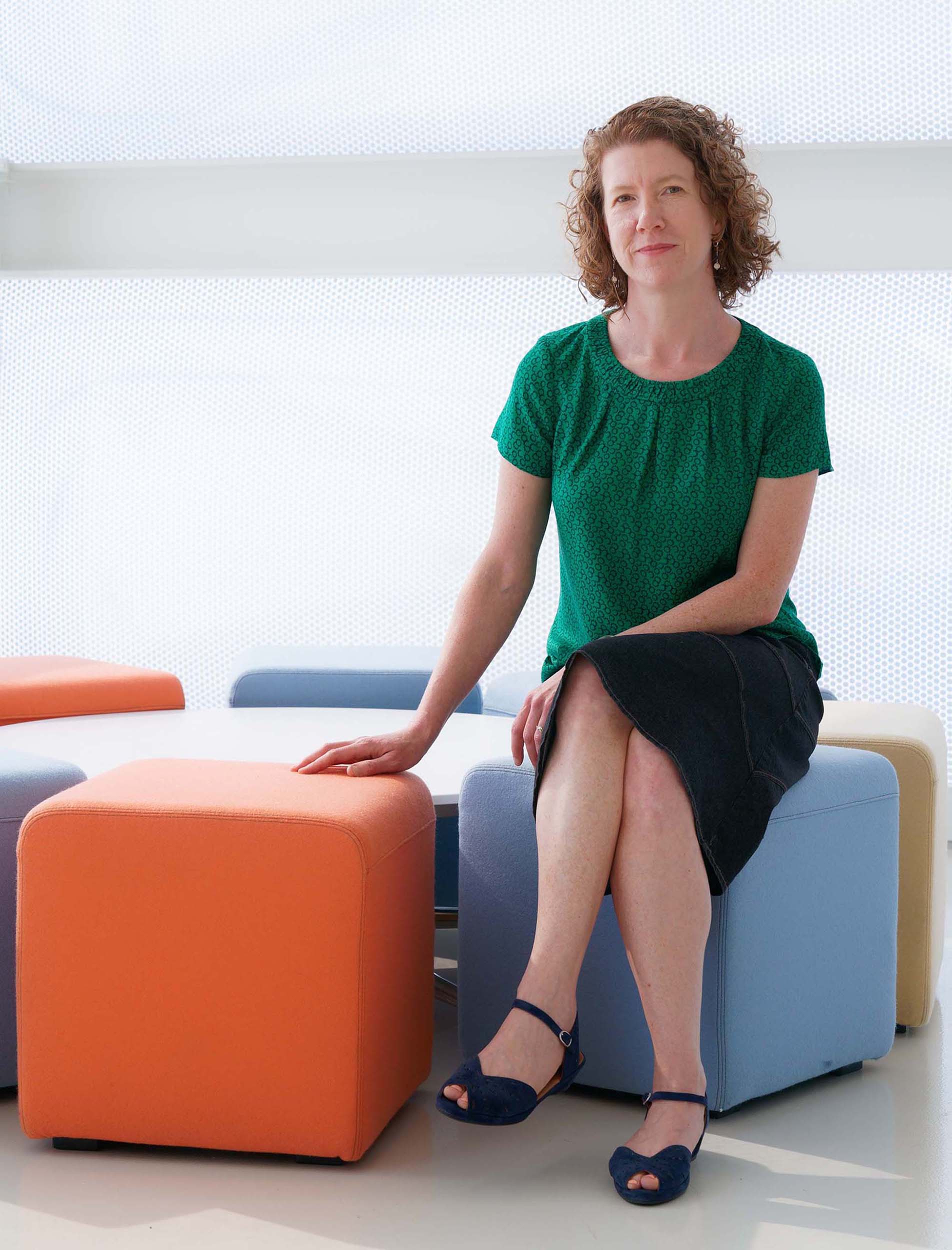 Jessica Meharry, sits on colorful cube shaped seating at ID