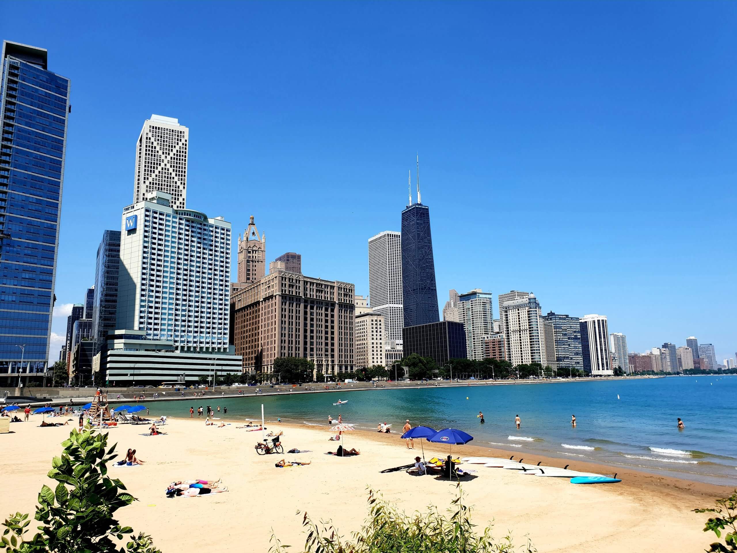 Beach with people and skyscrapers in background.