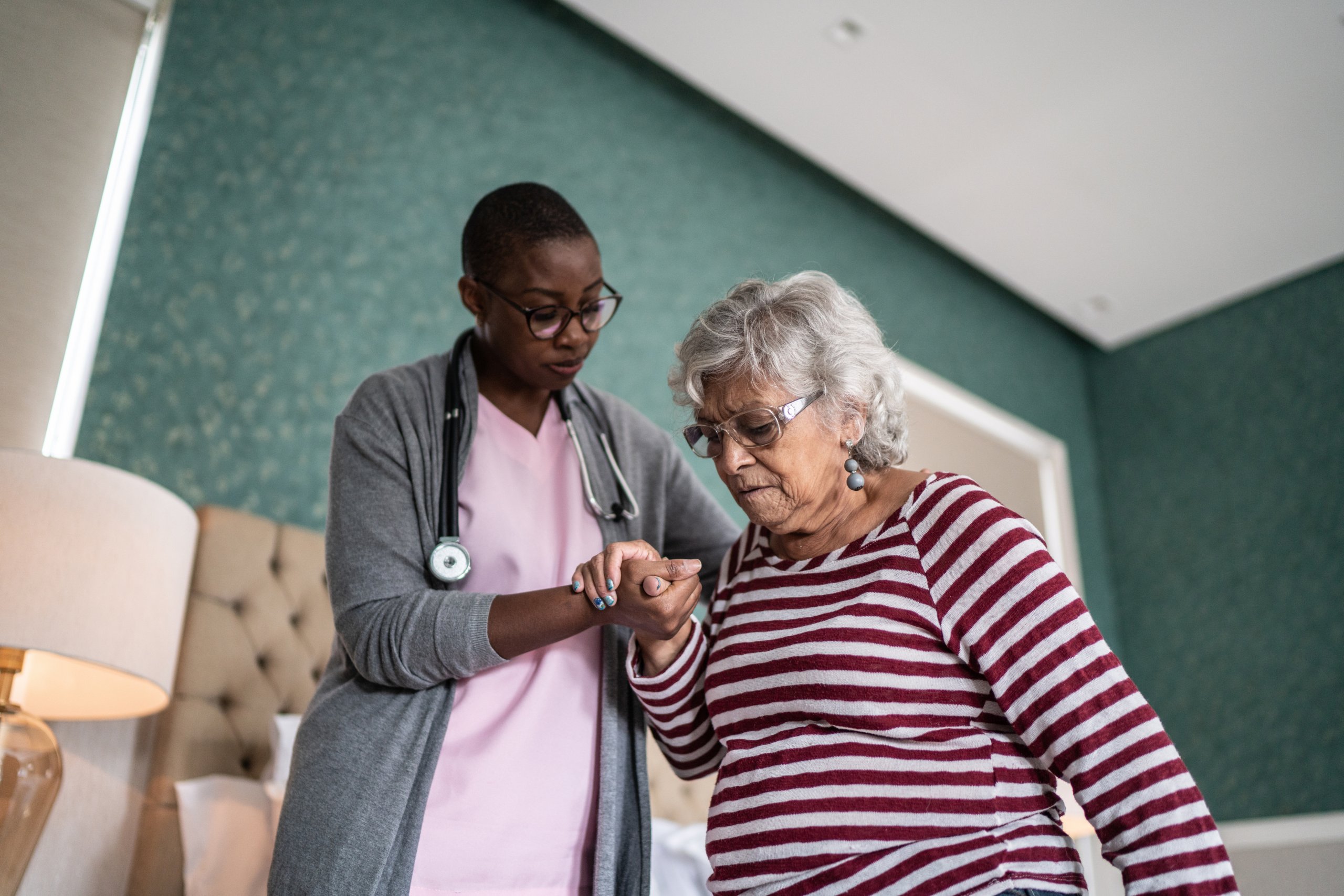 Nurse helping a senior woman standing in the bedroom