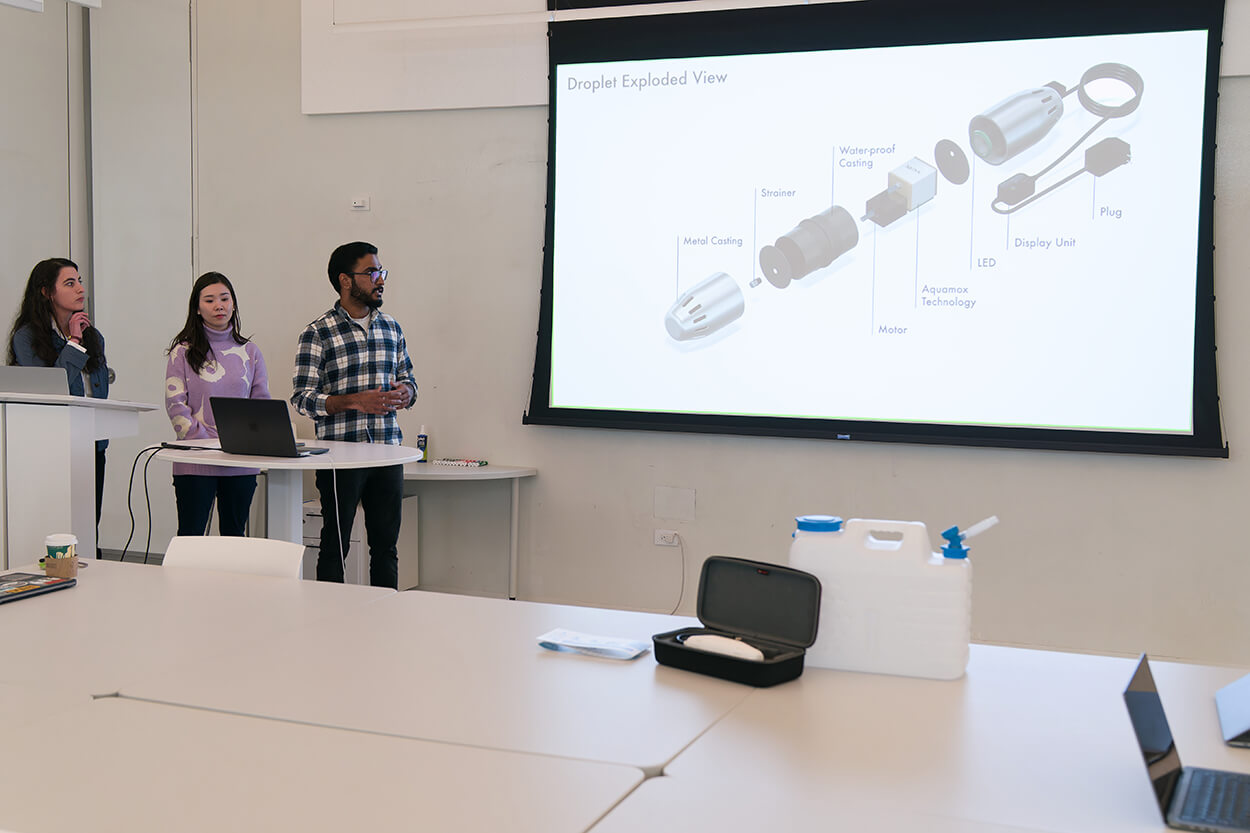 Team 3 students showing the rendering of their concept, Droplet, on a screen in the classroom.