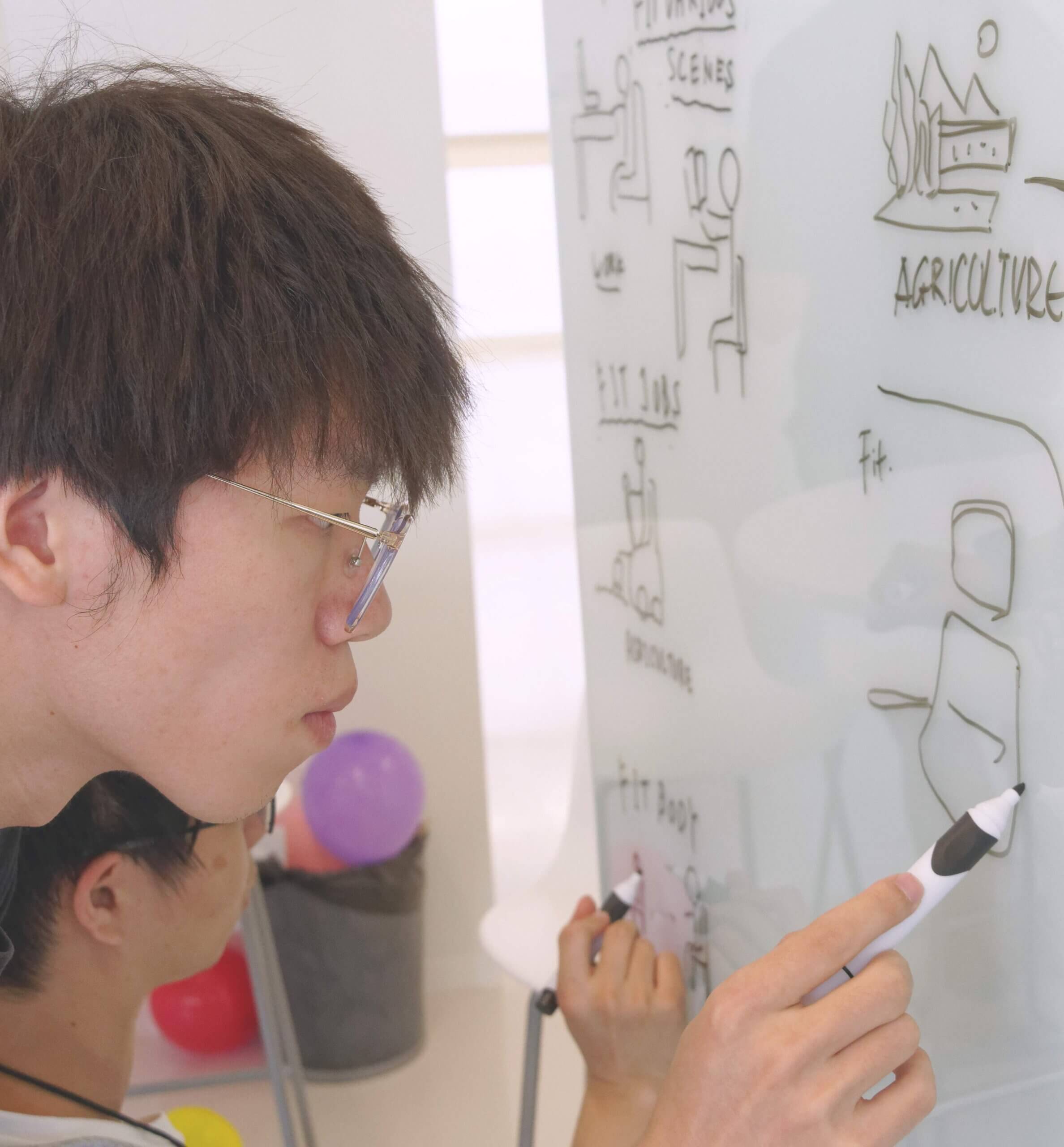 A photo of a student at a whiteboard in a university classroom.