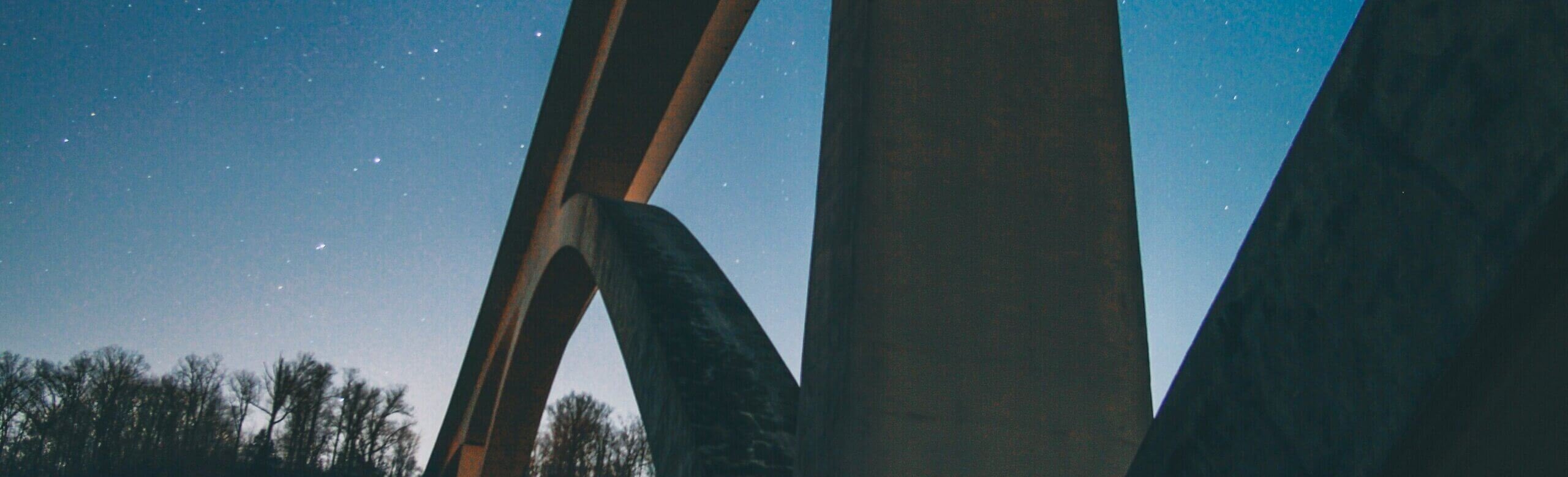 A photo of a bridge under a starry night sky.